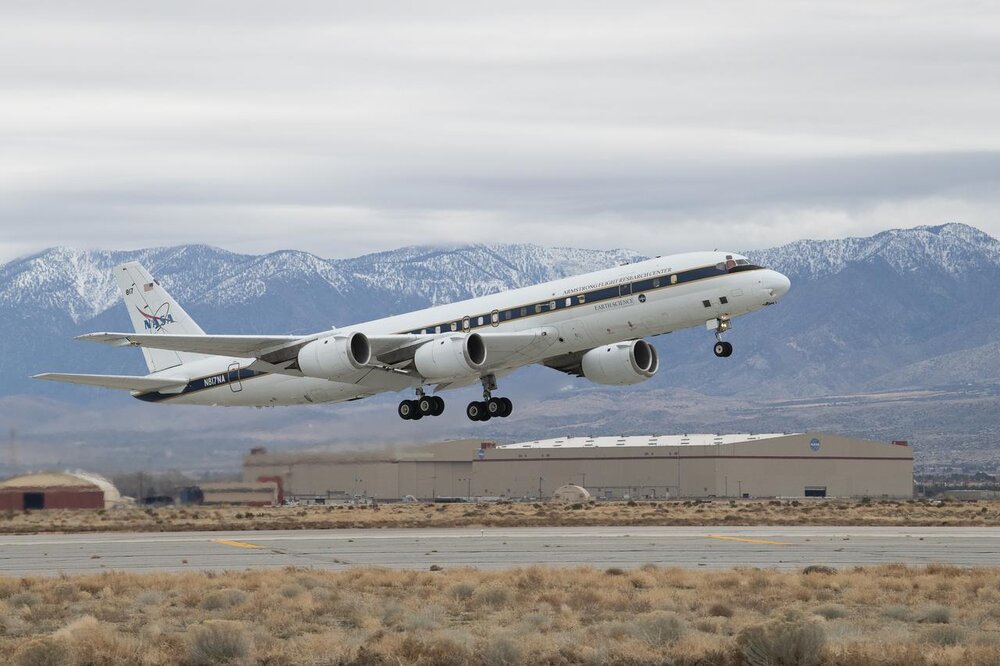 NASA research aircraft taking off from an airfield with a mountain range in the background.